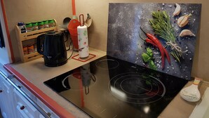 Una cucina con un piano cottura a induzione nero, una macchina per il caffè, un portarotolo di carta e una spezieria.