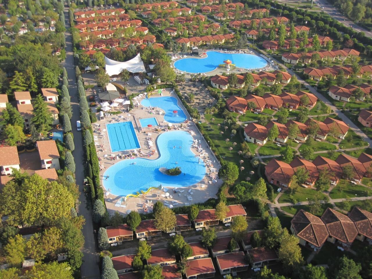 Vista aérea de un resort con múltiples piscinas, edificios residenciales organizados y jardines bien cuidados.