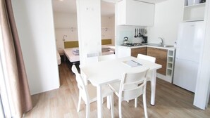 A compact kitchen with white cabinets, a dining table with chairs, and a small refrigerator.