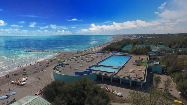 A resort with a large pool, beach area, and a view of the sea.