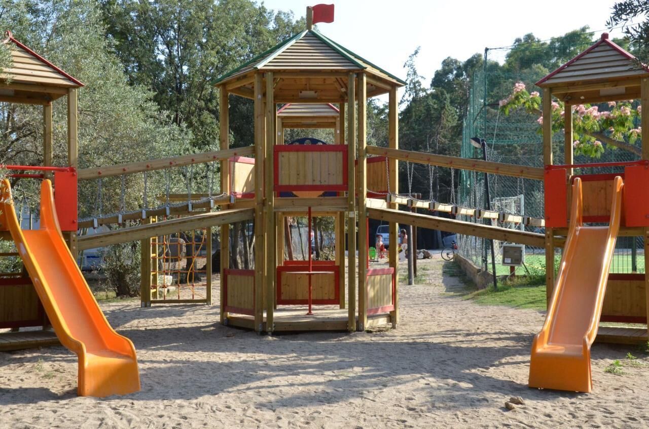 A wooden play structure with two slides and a central tower.