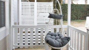 A wooden deck with a hanging chair and a white railing.