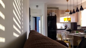 Eine moderne Küche mit einem schwarzen Kühlschrank, Holzschränken und Pendelleuchten.