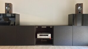 Ein modernes Wohnzimmer mit einer eingebauten Unterhaltungseinheit, einem Flachbildfernseher und zwei Wandlautsprechern.