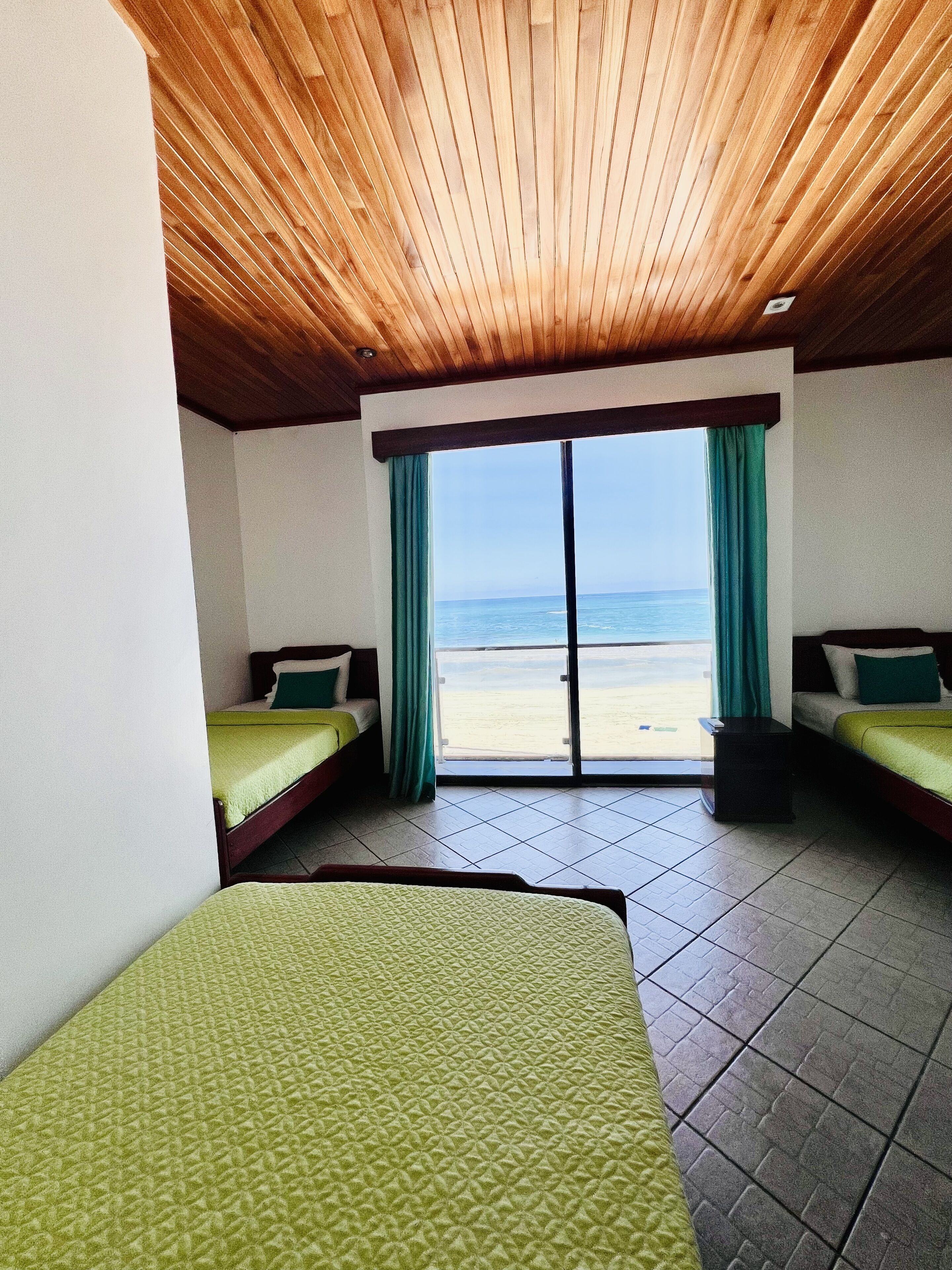 Ein Zimmer mit zwei Betten, Meerblick und Holzboden.