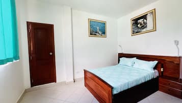 A bedroom with a wooden bed, white walls, and two framed pictures.