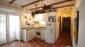A compact kitchen with white cabinets, a microwave, and a refrigerator. There is a window with a view of the outside, and a door leading to a balcony. - 200 Livingtarifa Drago (Tarifa)