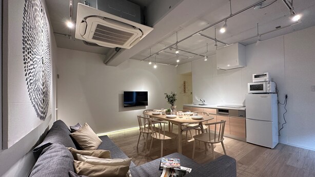 A modern living room with a sofa, dining table, and kitchen area. - Art BLDG (Hiroshima)
