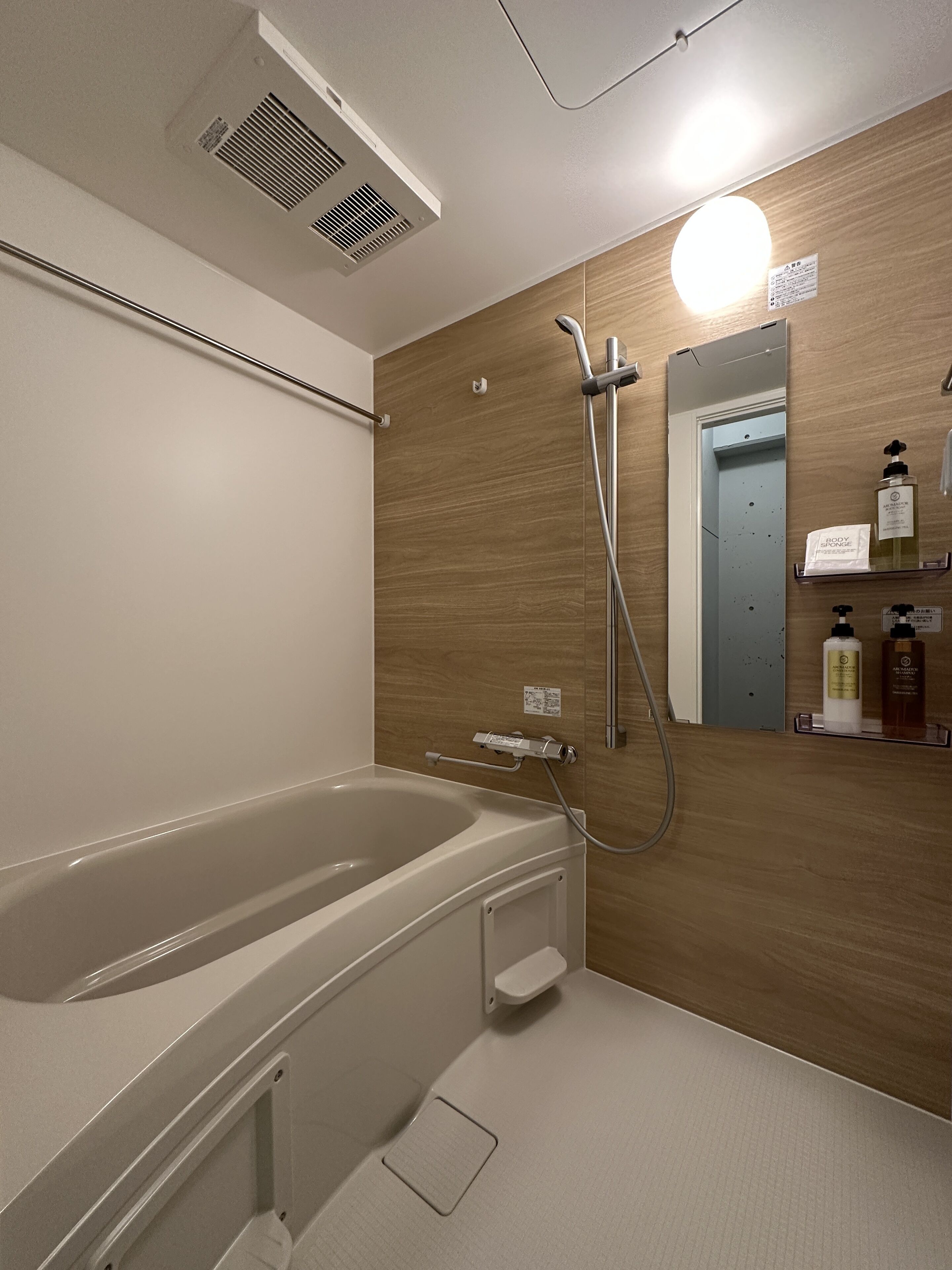 A modern bathroom with a large bathtub, a showerhead, and a mirror.