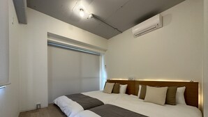 A hotel room with a large bed, a wooden headboard, a ceiling light, an air conditioning unit, and a window with blinds. - Art BLDG (Hiroshima)