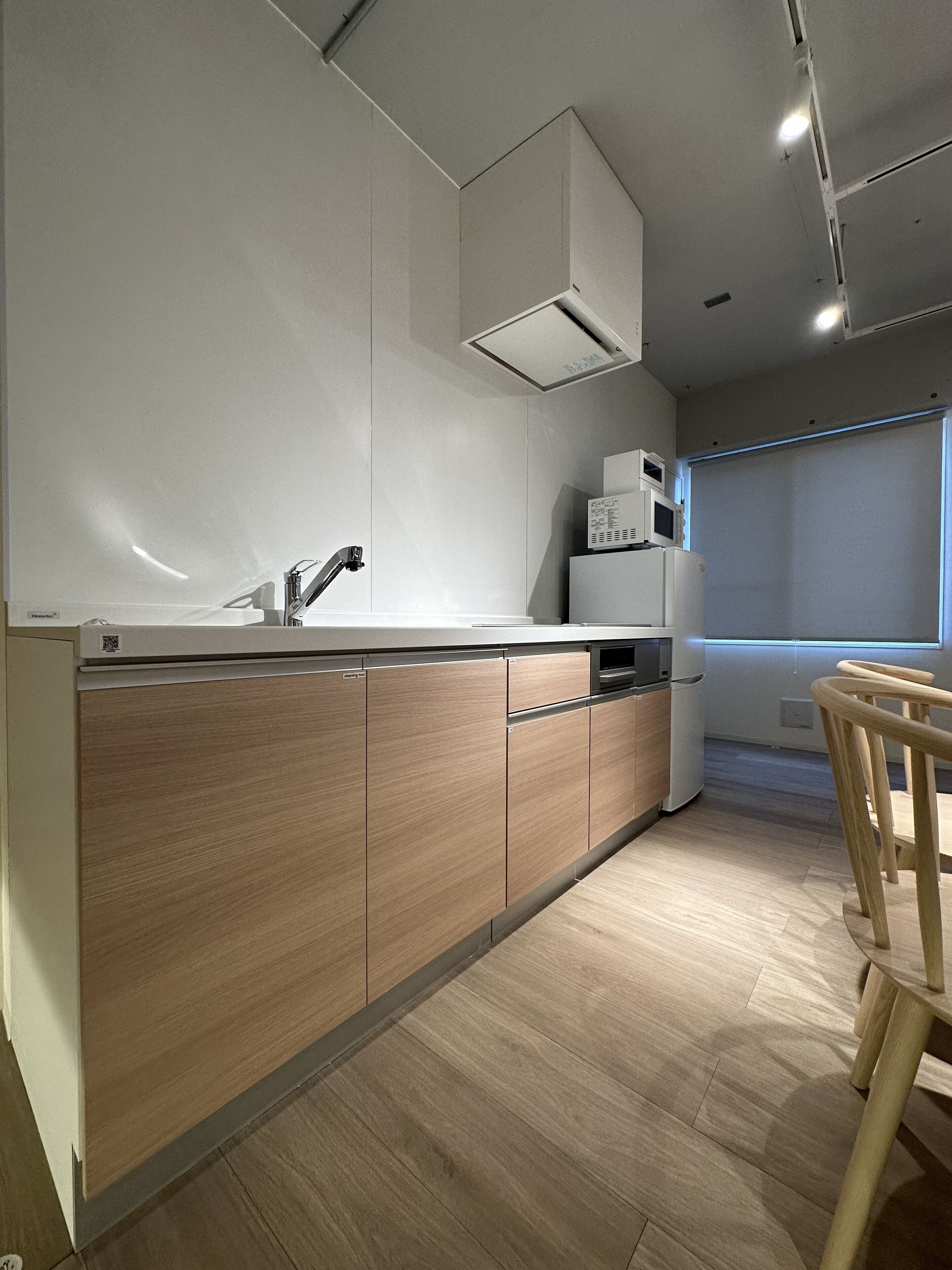 Una cocina moderna con armarios de madera, un lavamanos de acero inoxidable y un microondas integrado.