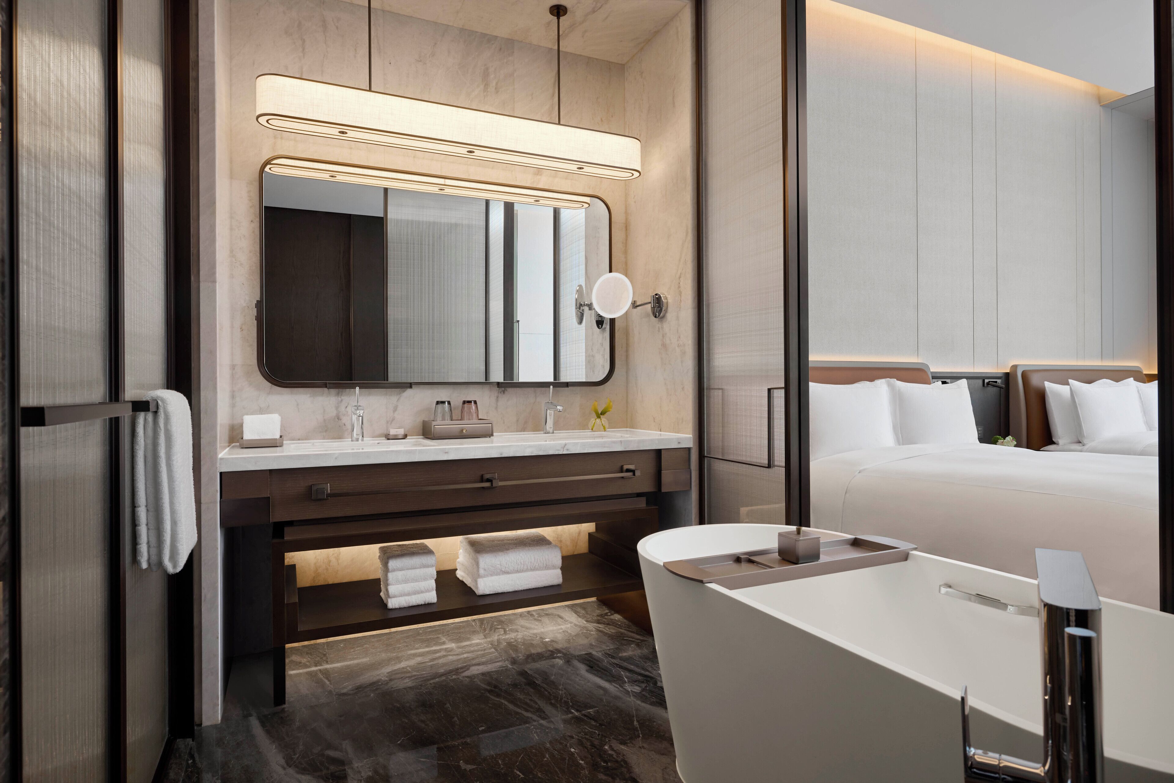 A modern hotel bathroom with a large mirror, a bathtub, and a vanity with a sink.