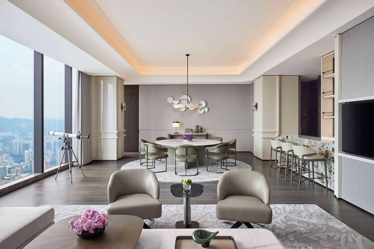 A modern living room with a large window, a dining area, and a bar.