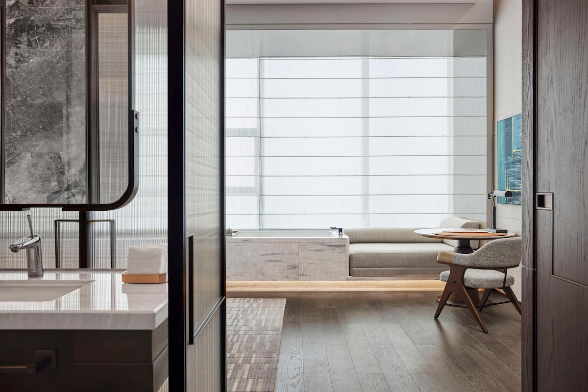 Un baño moderno con un espejo grande, un lavamanos y un perchero para toallas.