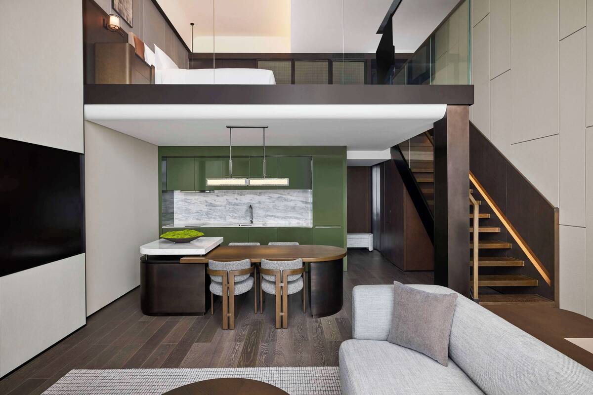 A modern interior with a dining area, a sofa, and a staircase.