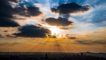 A city skyline at sunset with clouds and sunlight.