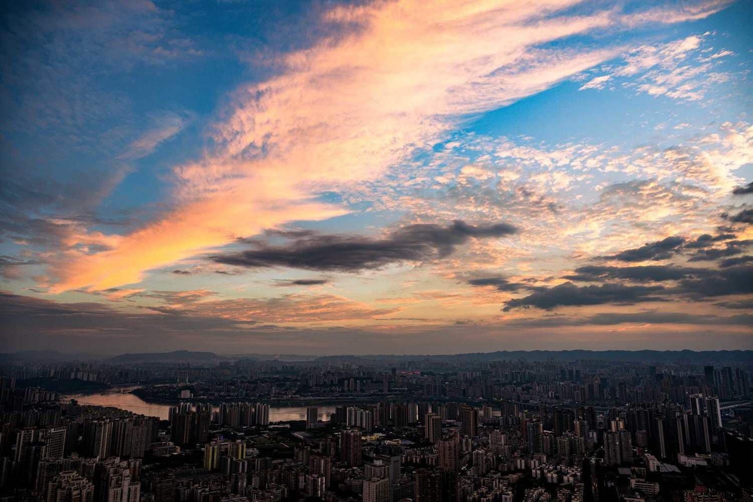 Un paisaje urbano con un río y un cielo al atardecer.