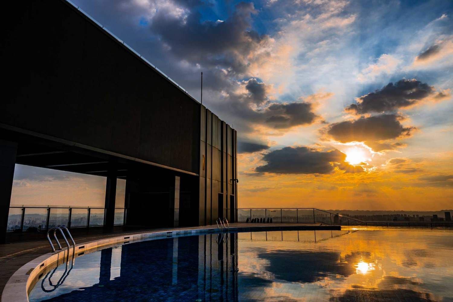 Un edificio moderno con piscina reflejando el atardecer.