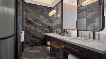 Un baño moderno con pared de mármol, un espejo grande y un tocador con una banca.
