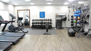 Un gimnasio con cintas de correr, mancuernas y pelotas de ejercicio.