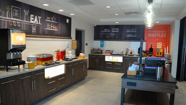 Una cocina moderna con armarios de madera oscura, una cafetera y una estación para hacer gofres.
