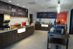 A modern kitchen with dark wood cabinets, a coffee machine, and a waffle station.