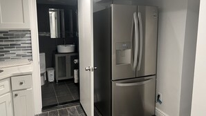 Een moderne keuken met een roestvrijstalen koelkast, een inbouwspoelbak en donkere betegelde vloeren.
