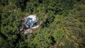 Ein Gebäude mit Kuppel, das von dichtem Wald umgeben ist, aus der Vogelperspektive.