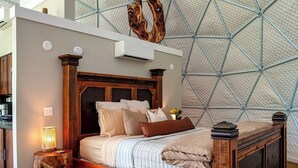 Ein Schlafzimmer mit einem hölzernen Bett, einer einzigartigen geometrischen Decke und einem rustikalen Nachttisch.