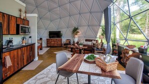 Ein großzügiger Wohnbereich mit einer großen, geometrischen Deckenkonstruktion, Holzmöbeln und einer Küchenzeile mit modernen Geräten.