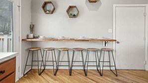 Una cocina con encimera de madera, cinco taburetes de bar y tres espejos hexagonales en la pared.