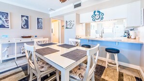 A modern kitchen with white cabinets, a blue countertop, and a clock above the sink.