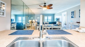 A modern kitchen with a double sink, a ceiling fan, and a dining area with a table and chairs.