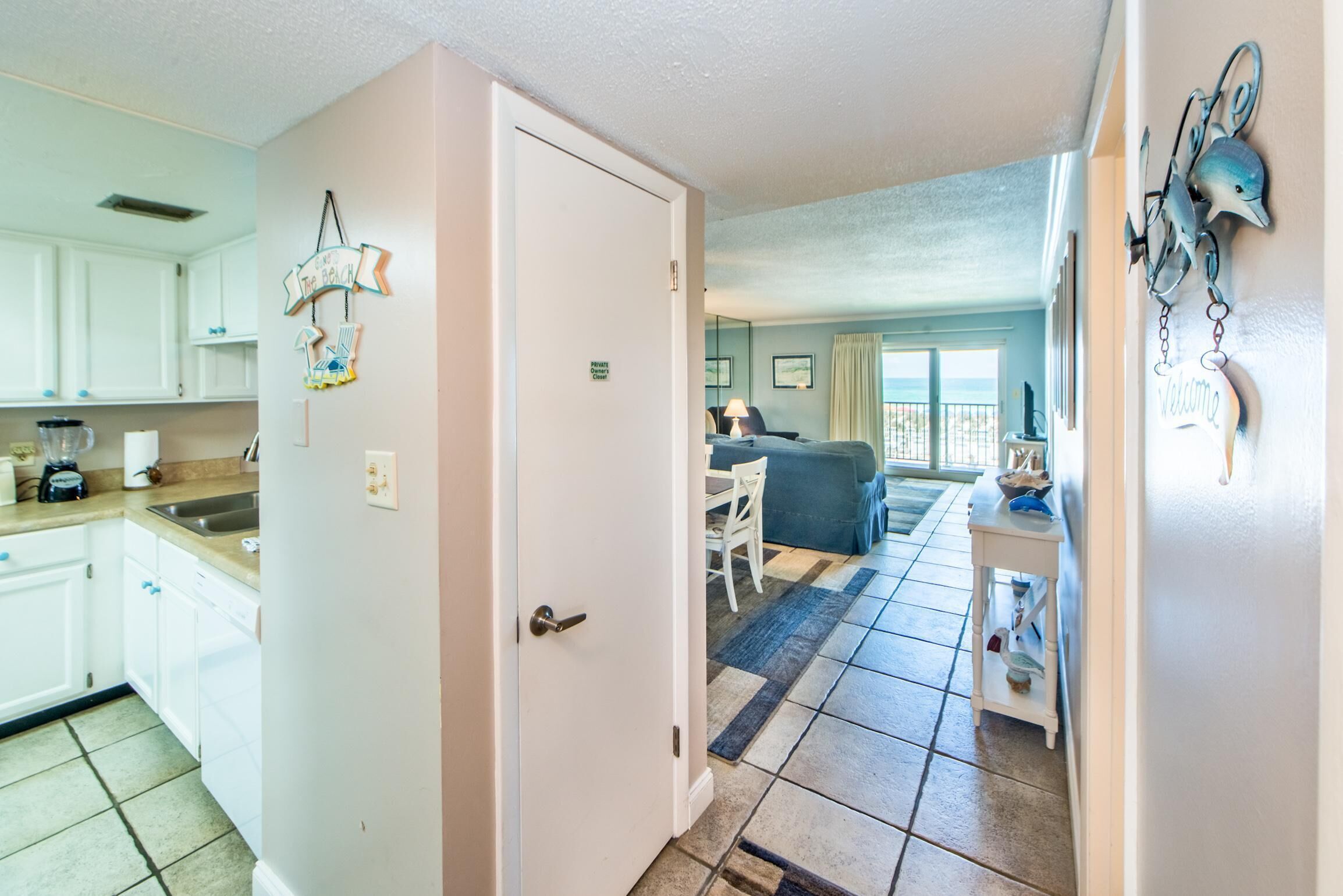 A compact kitchen with white cabinets and a dining area with a blue sofa.