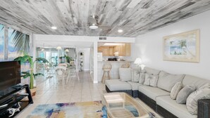 A spacious living area with a wooden ceiling, a sofa, a coffee table, and a television. - Mariner West 205 (Panama City Beach)