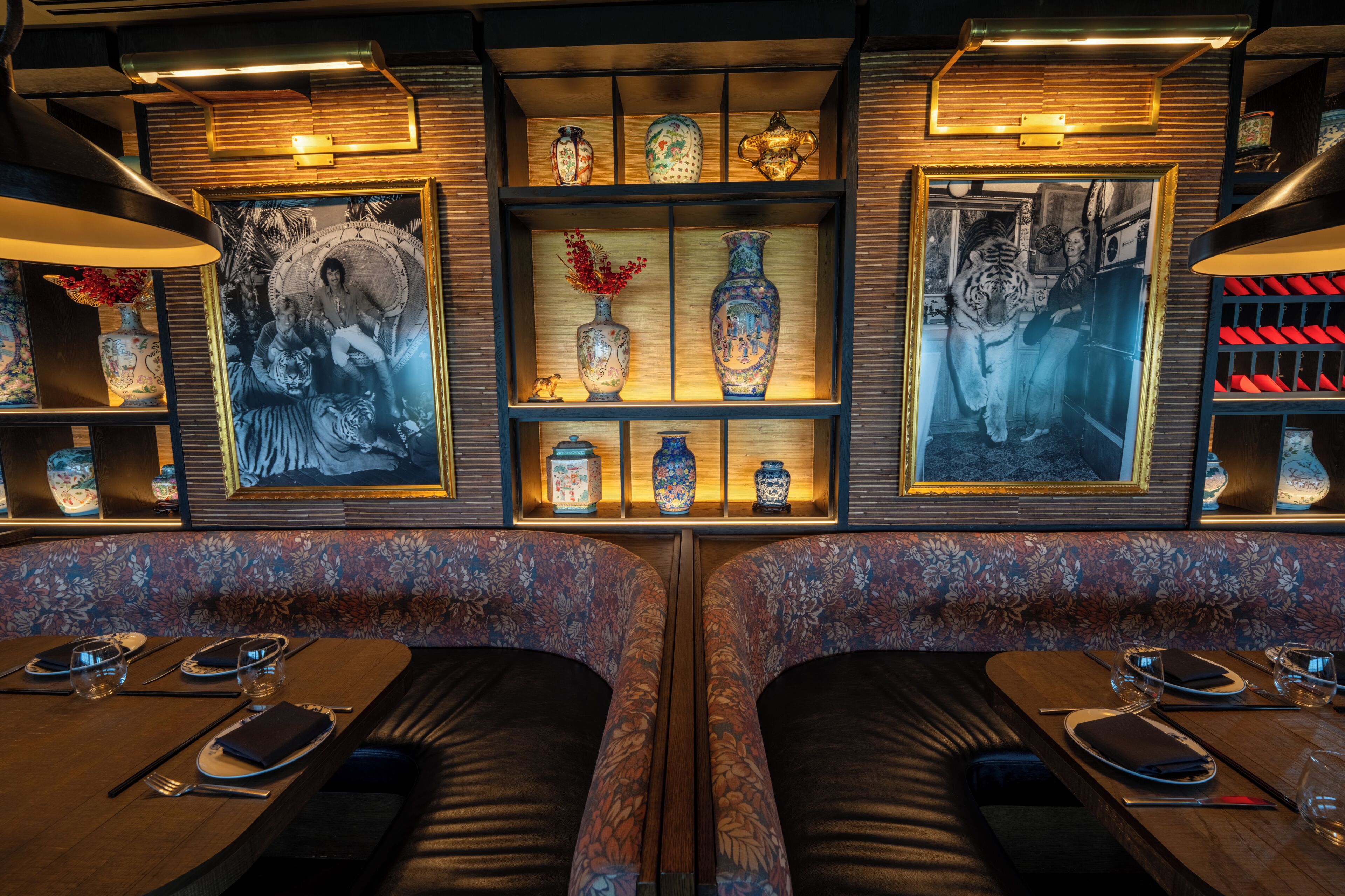 A restaurant with booths, a central dining table, and wall-mounted shelves with decorative items.
