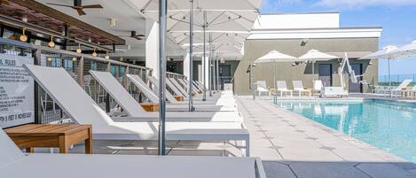 A poolside area with lounge chairs, umbrellas, and a pool.