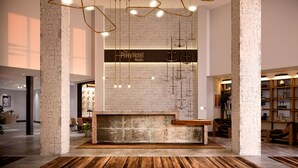A lobby with a rustic brick wall, hanging lights, a wooden reception desk, and a wooden floor. - The Perry Hotel Naples (Naples)