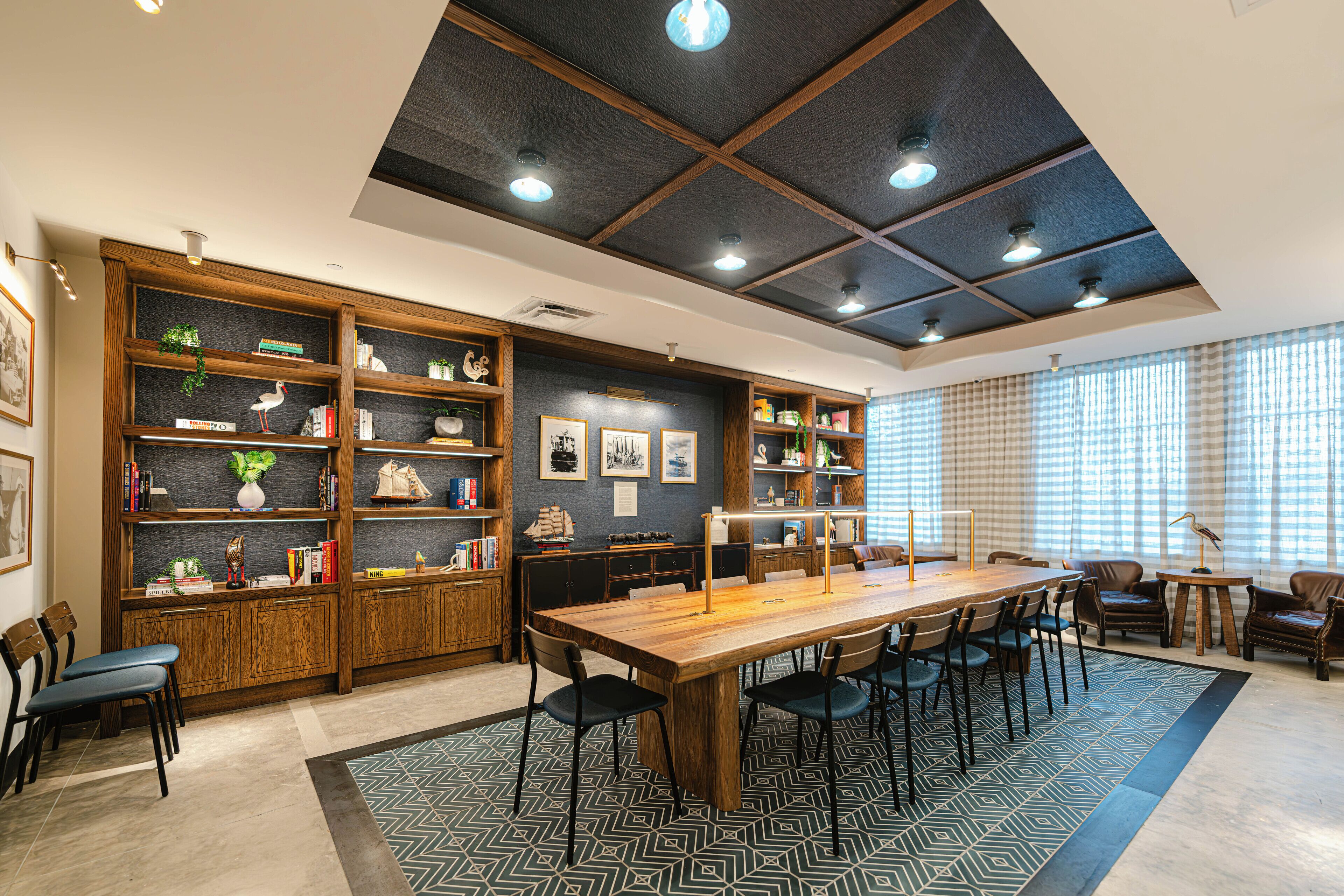 Una habitación amplia con una gran mesa de madera, varias sillas y estanterías empotradas llenas de libros y adornos.