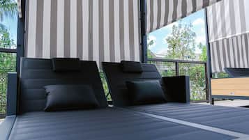 Une chambre à coucher moderne en plein air, avec deux lits noirs, des auvents à rayures et une vue sur la verdure.