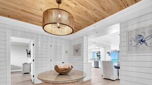 Ein modernes Interieur mit einem runden Glastisch, Holzboden und einer Decke mit Holzpaneelen.
