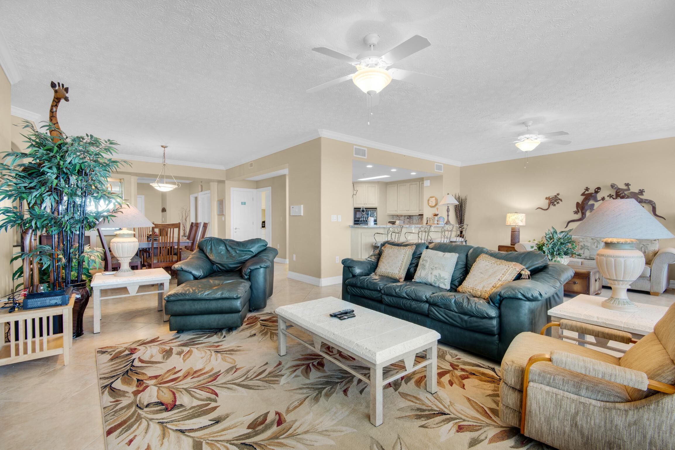 A spacious living room with a large sofa, a coffee table, and a decorative plant.