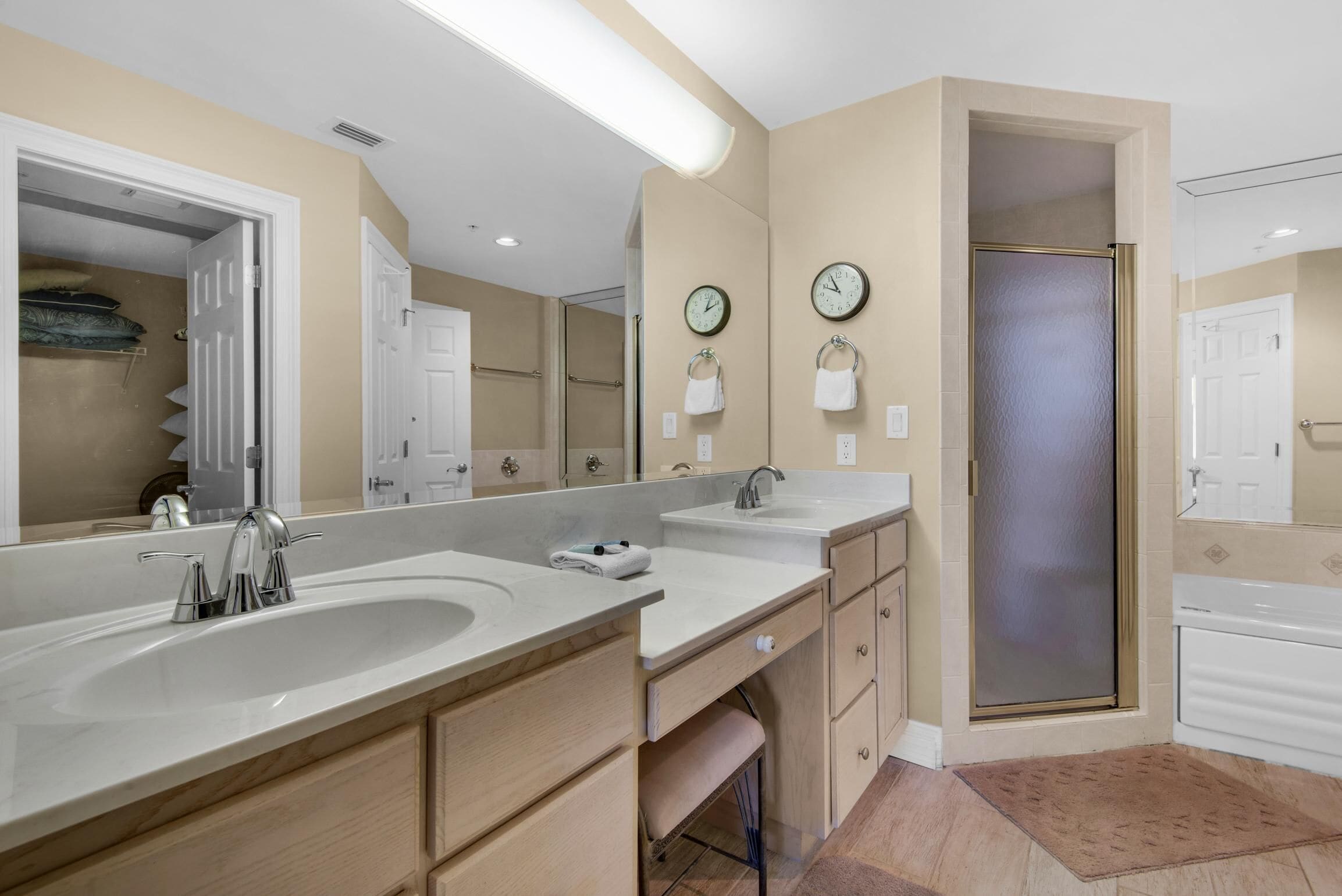 A bathroom with two sinks, a large mirror, and a shower with a frosted glass door.