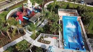 A water park with a flow rider, a pool, and palm trees. - Solara Resort -  5 bedrooms, Private Pool - FROZEN & HARRY POTTER - DISNEY AREA (Kissimmee)
