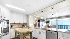 Une cuisine moderne avec des meubles blancs, des appareils en acier inoxydable et une table en bois.