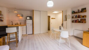 Una cocina moderna con microondas, armarios blancos y un comedor con una pequeña mesa y sillas.