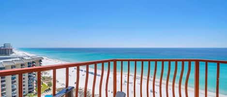 A balcony with a view of a beach and ocean.