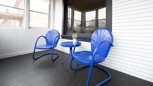 A covered porch with two blue rocking chairs and a small table. - Historic Hammond Home- Close to Duluth! Game Room & Pet Friendly: Dogs & Cats! (Superior)