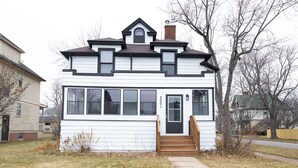 A two-story house with a front porch, a chimney, and a number '2001' on the door. - Historic Hammond Home- Close to Duluth! Game Room & Pet Friendly: Dogs & Cats! (Superior)