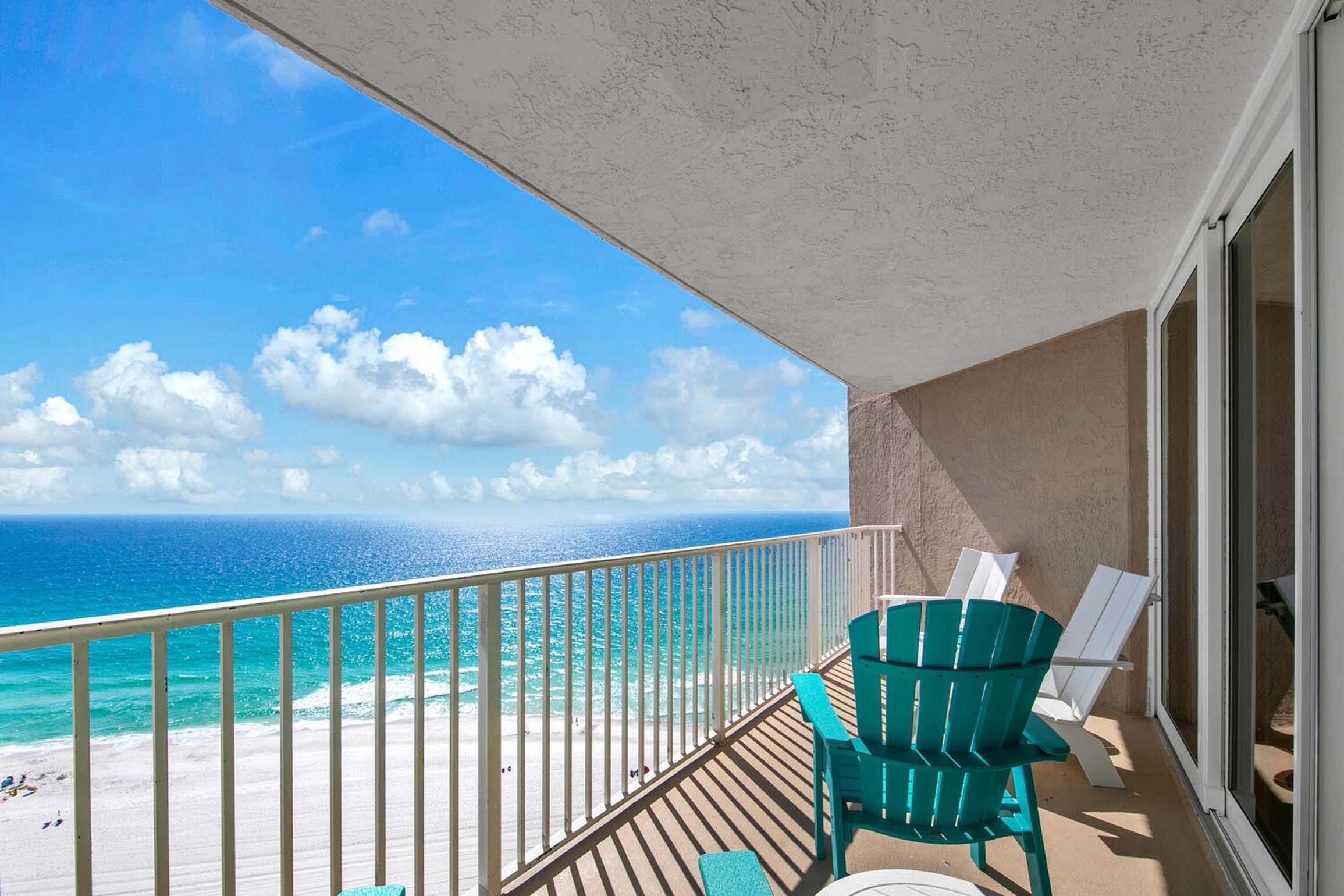Ein Balkon mit Blick aufs Meer, ein Holzboden und zwei grüne Stühle.